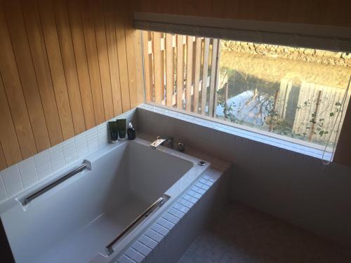 京丹后市Waterside Cottage Heron的带窗户的浴室设有大浴缸