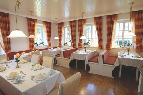 巴特法兴格豪斯黑尔德格德酒店的餐厅设有白色的桌椅和窗户。