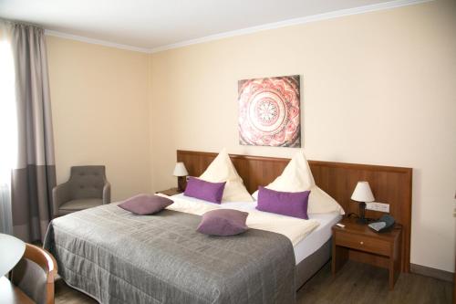 德罗尔斯哈根祖尔阿特恩凯尔旅馆的一间卧室配有一张带紫色枕头的大床