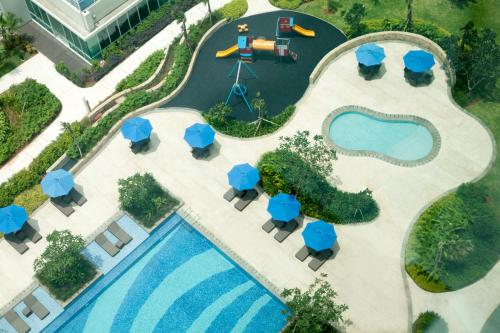 雅加达雅加达塞蒂亚布迪辉盛坊国际公寓的享有带桌子和蓝伞的度假村游泳池的顶部景致