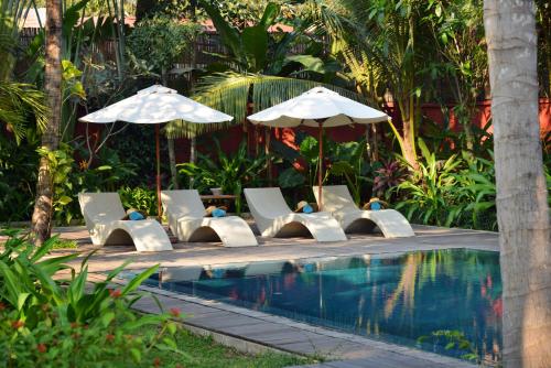 暹粒波兰卡大厦酒店的游泳池旁设有躺椅和遮阳伞的游泳池
