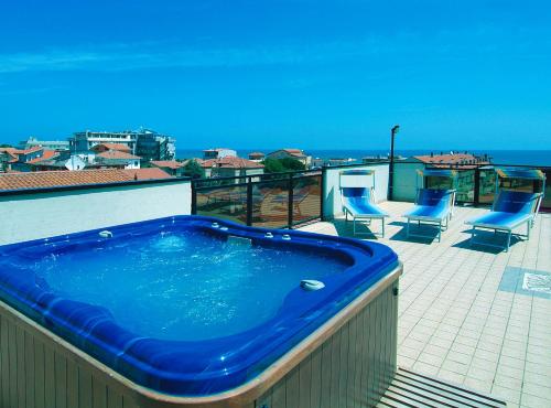 托尔托雷托Hotel Residence Margherita的阳台设有大型蓝色热水浴池和椅子