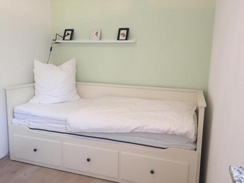 格洛韦Strandhaus Glowe的一张带白色床单和枕头的床