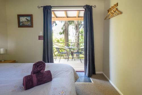 Kenepuru Sounds霍普韦尔山林小屋的一间卧室配有一张床,阳台配有桌子