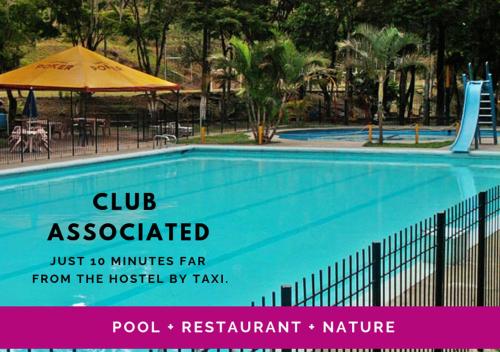 卡利赛事旅舍的一座游泳池,上面标有指示牌,上面写着俱乐部从医院乘出租车可到达