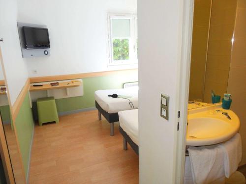 圣蒂博德维涅马恩河谷宜必思快捷酒店的客房设有两张床、一个水槽和浴缸。
