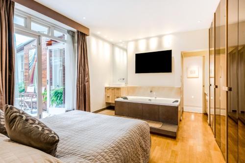 伦敦Garden Apartment in Central London的一间卧室配有一张床、一个浴缸和一台电视。
