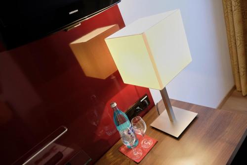 丁克尔斯比尔布劳尔赫克特浪漫酒店的桌子上的一盏灯,上面有一瓶和眼镜