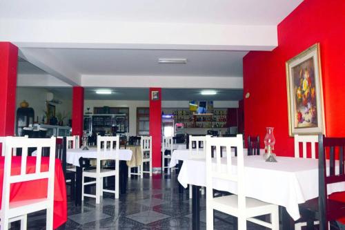 圣菲利佩Hotel Miramar Fogo Brava的用餐室设有白色桌子和红色墙壁