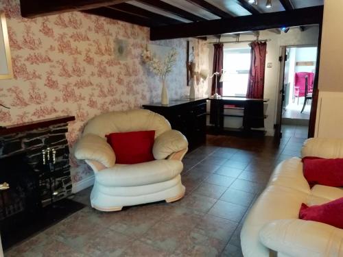 多尔顿因弗内斯Brown Cow Cottage的客厅配有两把白色椅子和壁炉