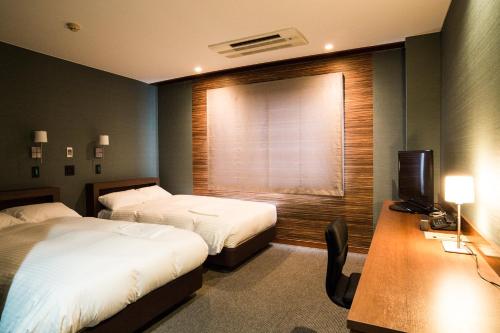 增田Hotel Daiei Masuda的酒店客房设有两张床、一张书桌和一个窗户。
