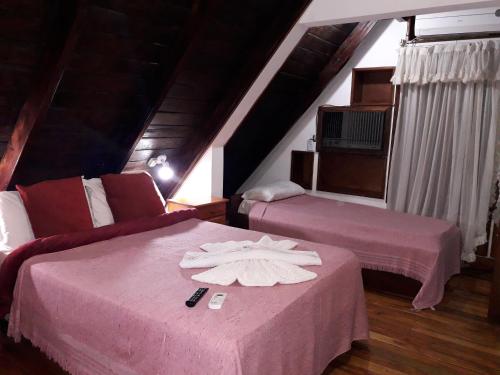 伊瓜苏港Petit Hotel Caraguata的配有粉红色床单和毛巾的客房内的两张床