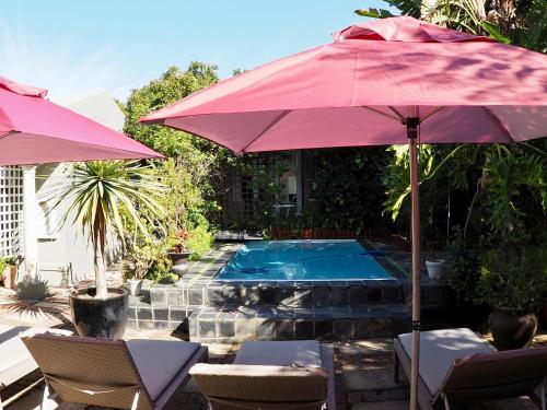 克尼斯纳Hillview Boutique Apartments的一个带红色遮阳伞和椅子的游泳池以及一个游泳池