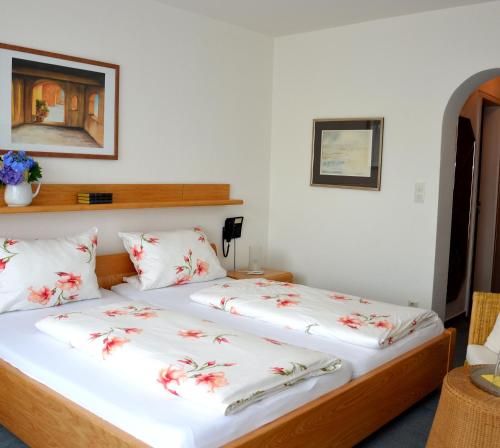 林道伊博耐特贾尼酒店的一间卧室配有两张带白色床单和红色鲜花的床。