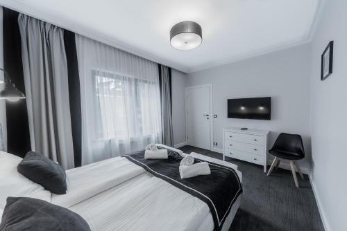 米兹多洛杰Apartamenty Feria的一间卧室配有一张床、一台电视和一把椅子