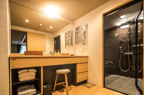 京都Homm Stay Nagi Arashiyama Kyoto By Banyan Group的一间带水槽、淋浴和凳子的浴室