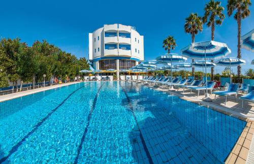 马帝斯兹罗Hotel Olimpic的大楼前的游泳池配有椅子和遮阳伞