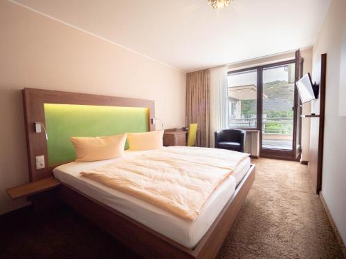安德纳赫莱茵河畔别墅酒店的一间卧室配有一张带绿色床头板的床和窗户