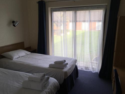 MinsterThe Abbey Hotel and conference centre的一间卧室设有两张床和一个带毛巾的窗户。
