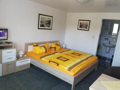 青斯特Zingster Ostseeklause的一间卧室配有一张带黄床单和水槽的床