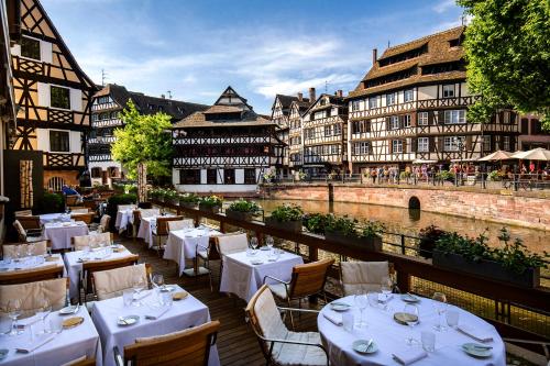 斯特拉斯堡Hotel & Spa REGENT PETITE FRANCE的一间设有白色桌椅的餐厅,位于河边