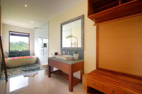 乌布DLobong Suite Ubud的带浴缸、水槽和镜子的浴室