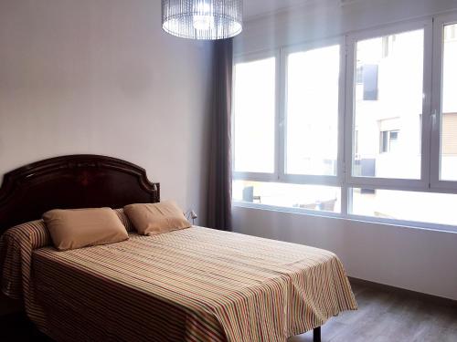 阿利坎特Alicante centre ,Plage et Quartier animé,Wifi Clim的一间卧室配有一张带条纹毯子的床和窗户。