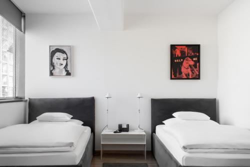 格拉茨Augarten Art Hotel, a Member of Design Hotels的白色墙壁客房的两张床