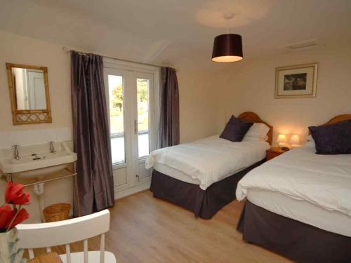 林茅斯Old Lyn Cottage的一间卧室设有两张床、一个水槽和一个窗口