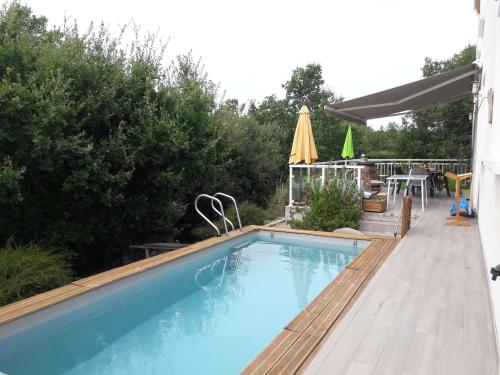 拉加里格La maison familiale的游泳池设有甲板、桌子和遮阳伞