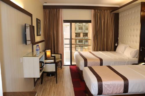 迪拜埃尔卡里大酒店的酒店客房设有两张床、一张书桌和一个窗户。