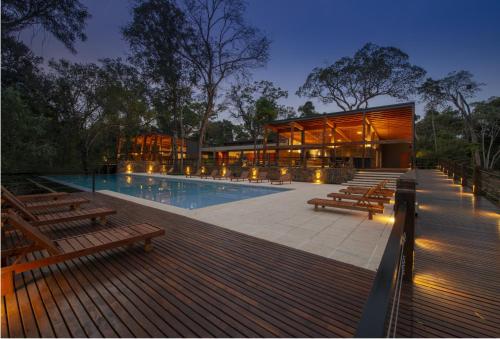 伊瓜苏港Selvaje Lodge Iguazu的一座带游泳池和木凳的房子