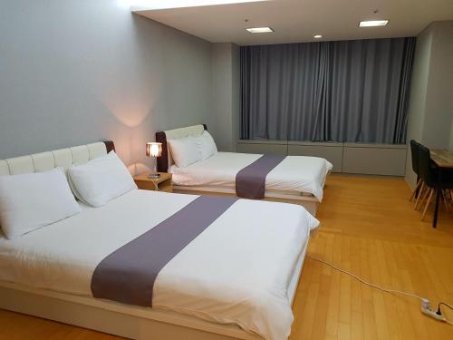 仁川市Sky Guestel的酒店客房带两张床和一张桌子以及椅子。