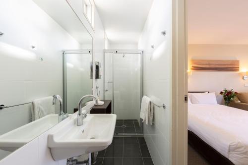 堪培拉ibis Styles Canberra Tall Trees的一间带水槽和淋浴的浴室以及一张床