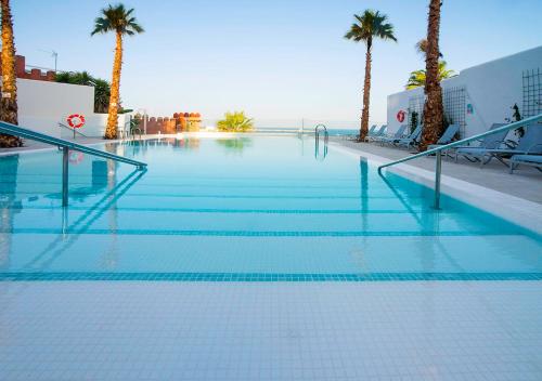 贝纳尔马德纳Hotel Benalmadena Beach的一座棕榈树和海洋的大型游泳池