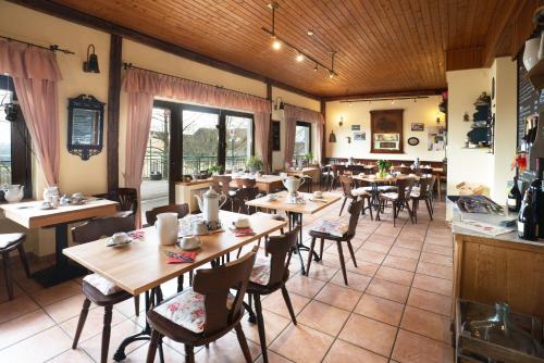 阿伦贝格祖尔布格斯查克餐厅酒店的餐厅设有木桌、椅子和窗户。
