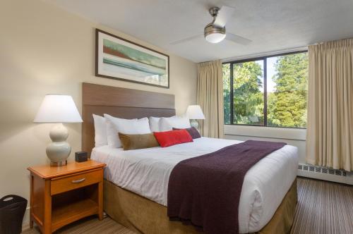 温哥华UBC西海岸套房公寓式酒店的一间卧室设有一张床和一个大窗户
