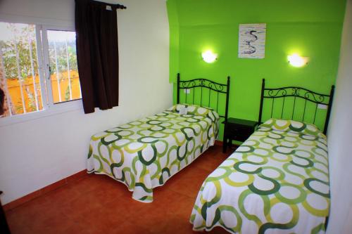 科斯塔德安提瓜Aparthotel la Piramide的绿墙客房内的两张床