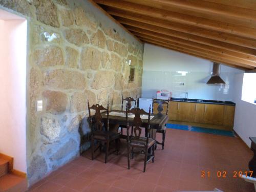 Oliveira de BarreirosCasa do Forno, Viseu的一间设有石墙和桌椅的用餐室