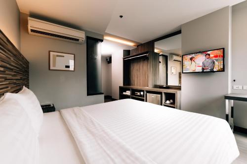 曼谷斯彭萨酒店的卧室配有白色的床和平面电视。