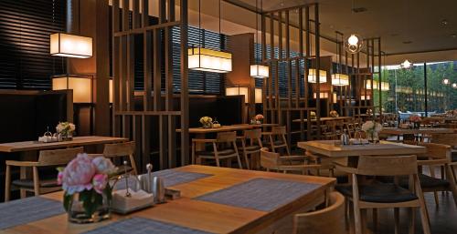 广州柏高·颂酒店广州金融城车陂南地铁站店的餐厅设有木桌和椅子及灯