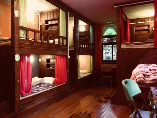 丽江汤姆家客栈的客房配有带红色窗帘的双层床。