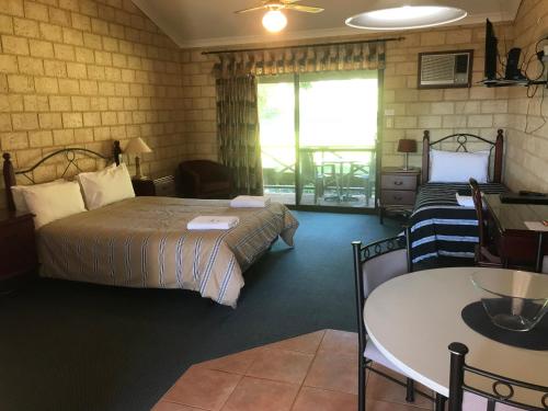 彭伯顿卡里森林汽车旅馆的酒店客房带两张床、一张桌子和一张桌子以及椅子。