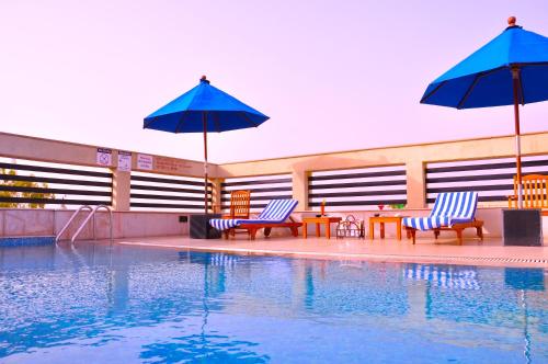 诺伊达Fortune Sector 27 Noida - Member ITC's Hotel Group的游泳池旁设有2把椅子和遮阳伞