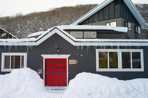 俱知安町Slowlife Lodge的雪中带红门的房子