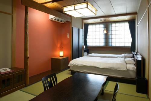 青森宿屋茶花酒店的卧室配有一张床和一张桌子及椅子