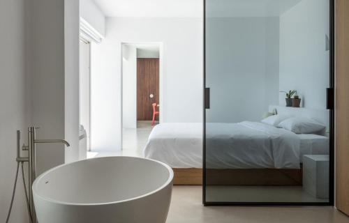 皮尔戈斯圣托里尼高地公寓的白色的浴室设有浴缸和床。