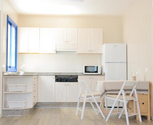 塞博河畔卡莱塔Apartamentos El Marinero - Caletilla的厨房配有白色橱柜和桌椅