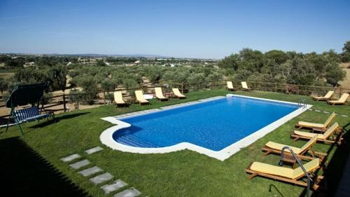 埃武拉奎因塔多斯巴斯托斯酒店的一个带椅子和一束家具的游泳池