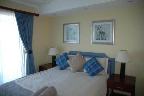 拉姆斯盖特Ramsgate Palms H的一间卧室配有一张带蓝色和白色枕头的床